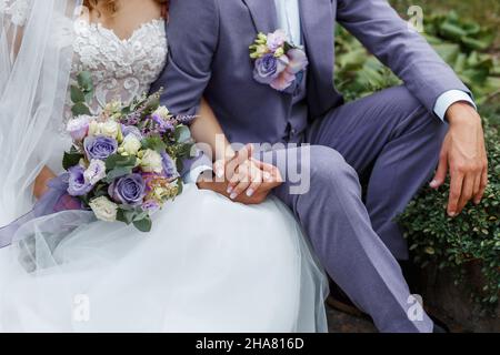 Couple hugging on their wedding. Trendy color of the year 2022 in wedding. Bride holding bouquet and embracing groom in Very Peri suit. Stock Photo