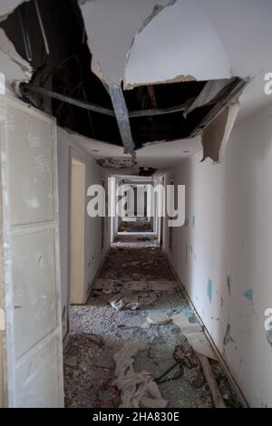 Scary empty dark corridor in an abandoned building. Shabby walls. The play of light and shadows in an abandoned house. Broken doors. An old abandoned Stock Photo