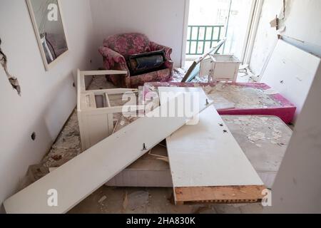 Pieces of broken glass among destroyed furniture and door in an abandoned old hotel rooms. Vandalism and damage. Stock Photo