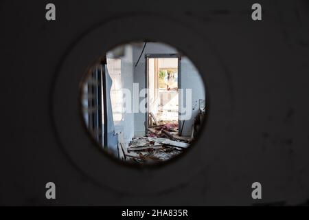 View through the round hole in the door on the Scary empty dark corridor in an abandoned building. Shabby walls. The play of light and shadows in an a Stock Photo