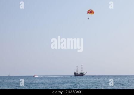 Tourists fly over the sea and the beach on a parachute. Sport and recreation for tourists in turkey. Stock Photo