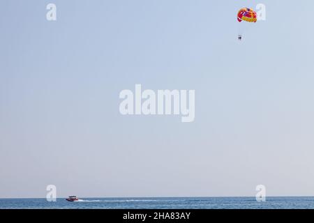 Tourists fly over the sea and the beach on a parachute. Sport and recreation for tourists in turkey. Stock Photo