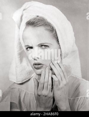 1950s WORRIED BLOND WOMAN TOWEL WRAPPED OVER HAIR CHECKING HER SKIN ON FACE FOR BLEMISH - a2888 CLE003 HARS WORRY CHECKING LIFESTYLE FEMALES MOODY HOME LIFE COPY SPACE LADIES PERSONS VANITY TEENAGE GIRL SKIN SPOT TROUBLED B&W CONCERNED SADNESS EYE CONTACT GROOMING HEAD AND SHOULDERS PRIDE MOOD GLUM WRINKLE COMPLEXION BLEMISH MID-ADULT MISERABLE BLACK AND WHITE CAUCASIAN ETHNICITY OLD FASHIONED VAIN Stock Photo