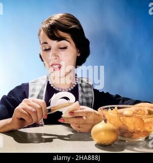 1950s 1960s WOMAN HOUSEWIFE COOK REACTING TO PEELING ONION CRYING TEARS - h2843c DEB001 HARS STUDIO SHOT GROWNUP TEARS HOME LIFE PREPARING COPY SPACE LADIES PERSONS GROWN-UP CRY HOMEMAKER PEOPLE STORY HOMEMAKERS HEAD AND SHOULDERS ONION HOUSEWIVES IRRITATION NOURISHMENT STYLISH ACID DEB001 IRRITANT SENSATION PEELING CHEMICAL REACTION EMOTION EMOTIONAL EMOTIONS MID-ADULT MID-ADULT WOMAN REACTION STINGING SULFUR YOUNG ADULT WOMAN CAUCASIAN ETHNICITY OLD FASHIONED ONIONS Stock Photo