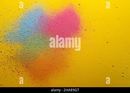 Multicolored, bright powder scattered on a yellow background. Copy space. Abstract texture. Top view.  Stock Photo