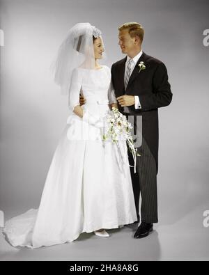 1960s PORTRAIT OF BRIDE AND GROOM STANDING SIDE BY SIDE - kb5520 HAR001 HARS LIFESTYLE CELEBRATION FEMALES MARRIED STUDIO SHOT ROSES EVENT SPOUSE HUSBANDS COPY SPACE FRIENDSHIP FULL-LENGTH LADIES MARRIAGE PERSONS INSPIRATION CARING MALES VEIL CONFIDENCE CEREMONY PARTNER BRIDAL DREAMS HAPPINESS ADVENTURE BRIDES STYLES CUSTOM AND EXCITEMENT TRADITION NUPTIAL NUPTIALS OCCASION MARRYING PRIDE RELATIONSHIPS CONNECTION CONCEPTUAL RITE OF PASSAGE STYLISH WED MORNING COAT PERSONAL ATTACHMENT AFFECTION COOPERATION EMOTION FASHIONS MARRY MATRIMONY MID-ADULT MID-ADULT MAN MID-ADULT WOMAN TOGETHERNESS Stock Photo