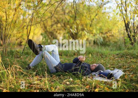 Teenager lies on the grass and rests in the park Stock Photo