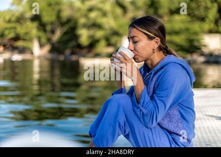 Latin girl with drinking coffee tea by a lake in a summer morning Stock Photo