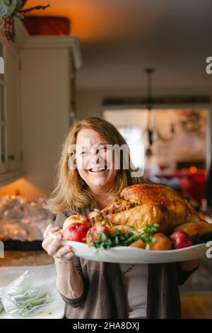 Laughing Grandmother presenting a cooked turkey on Thanksgiving Stock Photo