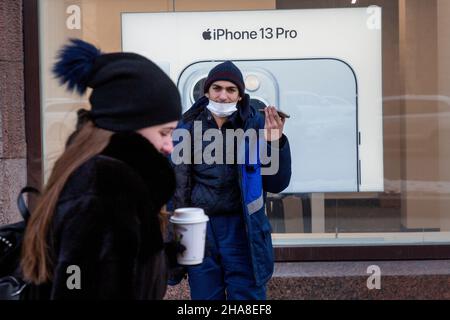 Moscow, Russia. 11th of December, 2021 A girl walks down the street with a coffee on the background of an advertisement for the Iphone 13 Pro phone in a Apple store on Tverskaya street in Moscow, Russia Stock Photo