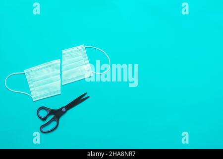 medical mask cut into 2 parts and scissors with space for text. View from above. Stock Photo