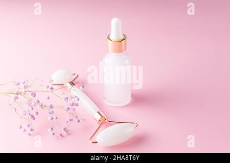 Beautiful composition of mockup serum bottle, pink face roller on pink background. Creative trendy beauty shoot with copy space. Stock Photo