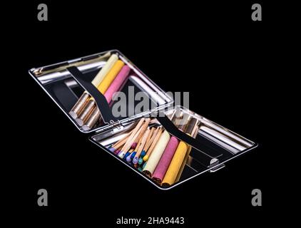 Metal tobacco box with color cigarettes and matchsticks on a black background Stock Photo