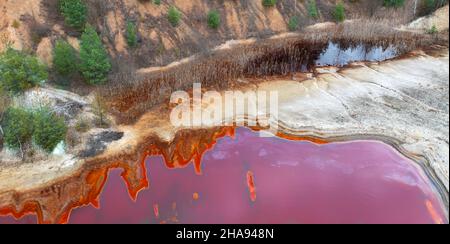 Mining of ores of various metals. Red toxic water in the reservoir of the mining and processing plant. Drone view. Stock Photo