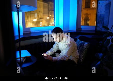 Exhausted young businessman texting family about staying at work overtime. Overwork and tiredness Stock Photo