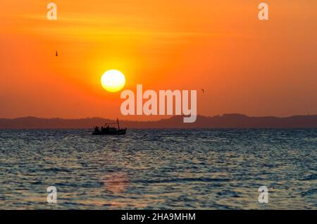 Sunset seen from Ribeira beach in Salvador, Bahia, Brazil. A boat sails at sea. Stock Photo