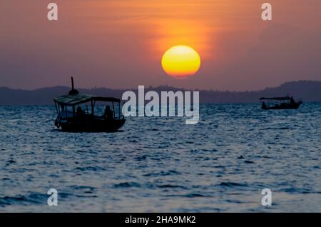 Sunset seen from Ribeira beach in Salvador, Bahia, Brazil. A boat sails at sea. Stock Photo