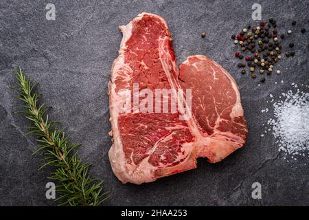 Raw Porterhouse Steak with Rosemary, Cracked Pepper, and Kosher Salt Stock Photo