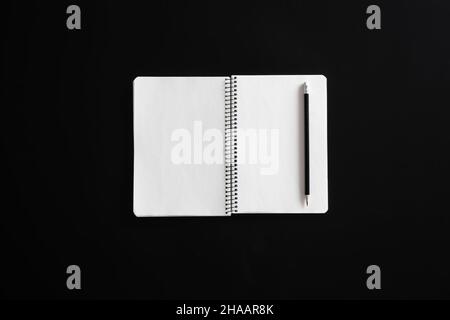 Open blank notebook on springs on black background, flat lay. Stock Photo