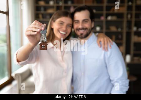 Happy young family couple of tenants receiving, holding keys Stock Photo