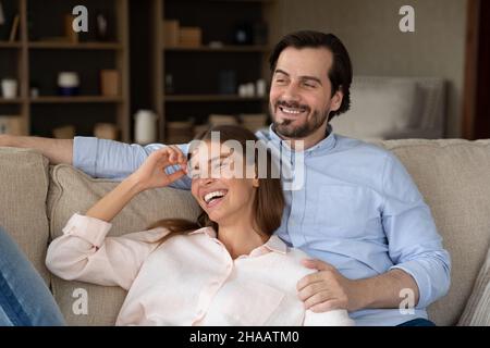 Cheerful dreamy young couple resting lying on sofa Stock Photo
