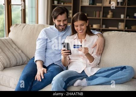 Happy couple of customers using mobile phone for shopping online Stock Photo