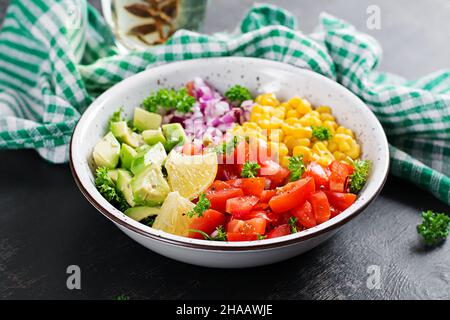 Salad with avocado, tomatoes, red onions and sweet corn in bowl. Vegetarian buddha bowl. Vegan food. Stock Photo