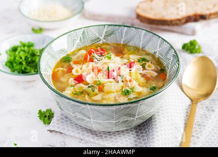 Minestrone, italian vegetable soup with pasta on light table. Stock Photo