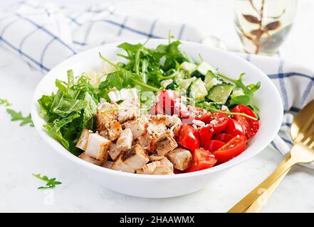 Grilled chicken fillet and fresh vegetable salad of lettuce, arugula, cucumber tomato and cheese. Healthy lunch menu. Diet food. Stock Photo