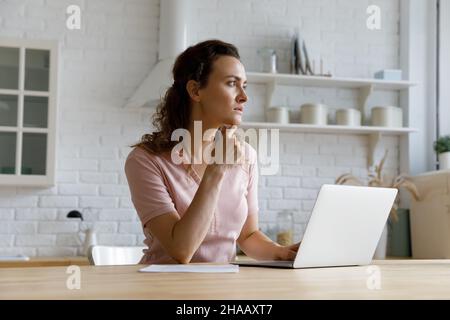 Serious thoughtful freelance employee woman working at laptop from home Stock Photo