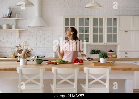 Cheerful excited homeowner woman enjoying cooking in kitchen Stock Photo