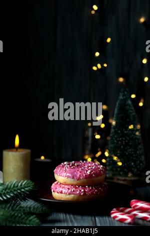 Donuts with colored caramel powder and pink icing on the background of Christmas decorations. Stock Photo