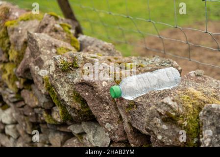empty discarded water bottle on a dry stone wall, environmental issue Stock Photo