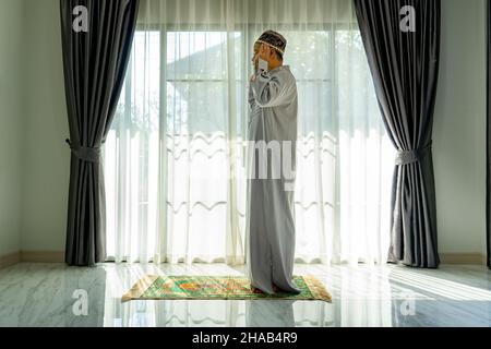 Muslim man praying in Living room at Home. Religion Duty Diary.  Silhouette of people Stock Photo
