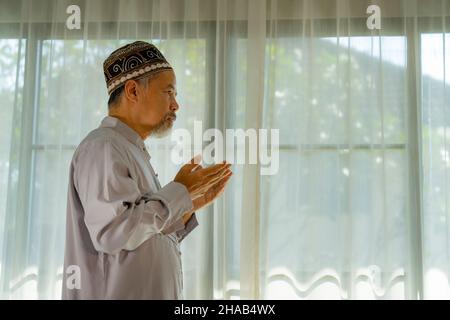 Muslim man praying in Living room at Home. Religion Duty Diary.  Silhouette of people Stock Photo