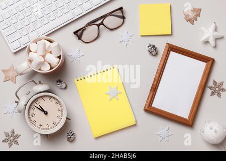 Christmas winter desktop. Ornament glasses keyboard alarm clock marshmallow frame on a gray table. Flat lay top view Stock Photo