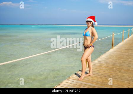 smiling young woman in santa hat on wooden pontoon Stock Photo