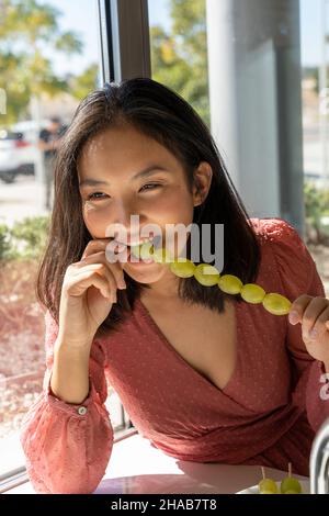 woman swallow a grape in her mouth, tasting its flavor, close-up vertical view Stock Photo