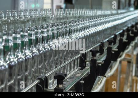 Conveyor with line of bottles for alcohol drinks in shop Stock Photo