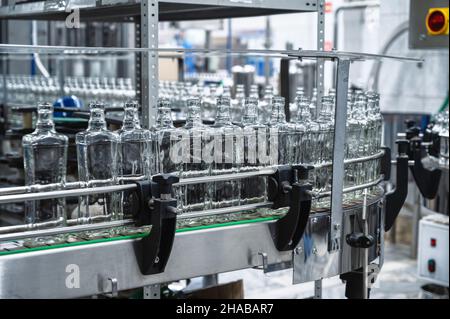 Conveyor belt transports empty glass bottles in workshop Stock Photo