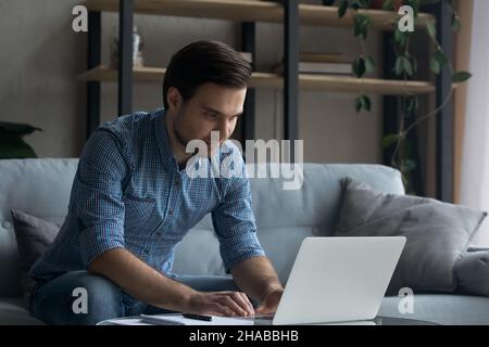 Young handsome man working on laptop at home Stock Photo