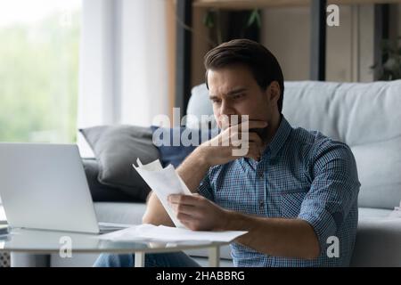 Man holds checks feels stressed due lack of money Stock Photo