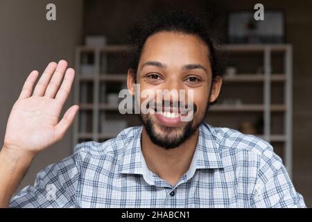 Closeup smiling African guy wave hand start videocall webcam view Stock Photo