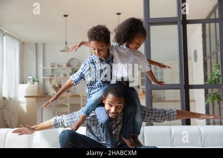 African dad and kids play together planes at home Stock Photo