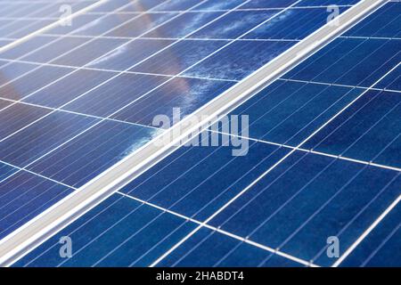Close-up of blue-colored solar panels from a tilted perspective. A beam of light from the sun enters from an upper corner. Stock Photo