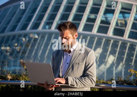 businessman with laptop in an urban setting modern buildings in background Stock Photo
