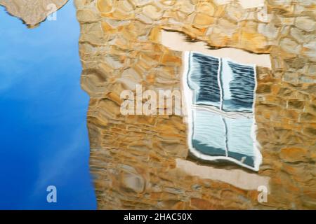 The reflection of a stone built house on the surface of water in the Leeds and Liverpool Canal Skipton Stock Photo