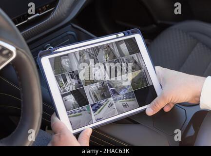 man hands holding digital tablet with multiple camera views Stock Photo