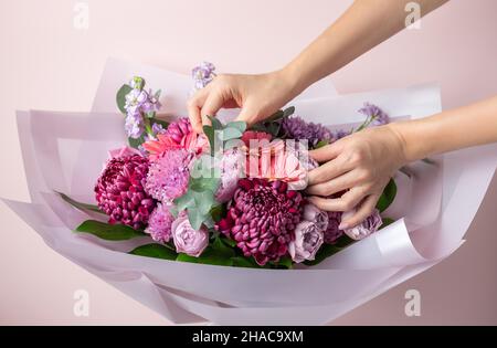 Female florist creating bouquet of mixed flowers. Delivery fresh cut flower. Floristics workshop. Stock Photo