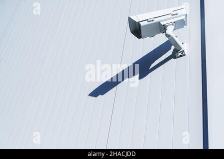 White street surveillance camera on the white wall of the building. Total control and security Stock Photo